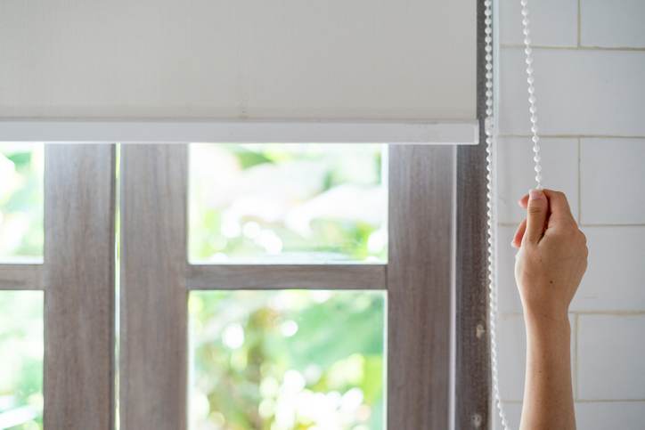 Woman pull rope, opened modern white  blinds