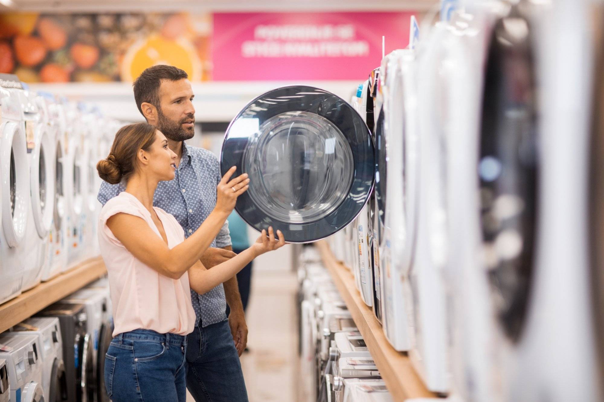 Young couple looking for a proper drying machine Young couple seen in a home appliances store in front of a drying machine.